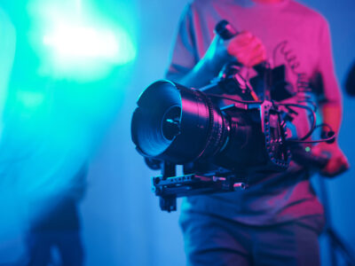 Close-up of young cameraman shooting with professional camera while making content in studio