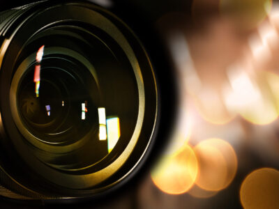Camera lens against blurred lights, bokeh effect. Banner design